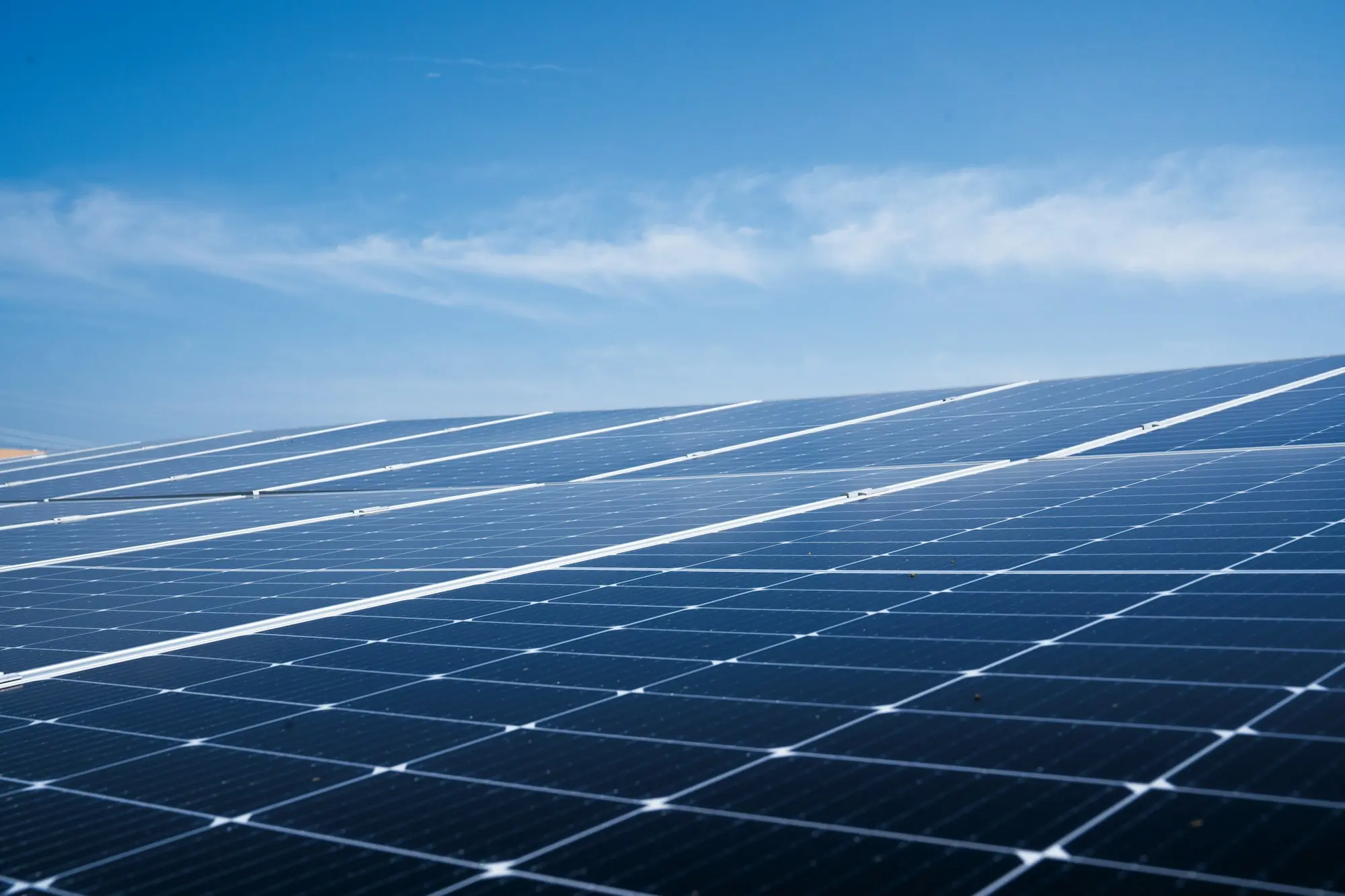 Reihen von Solarmodulen unter blauem Himmel mit feinen Wolken